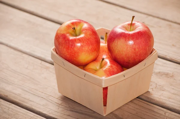 Pommes dans un panier en bois sur fond de panneau de bois rustique — Photo