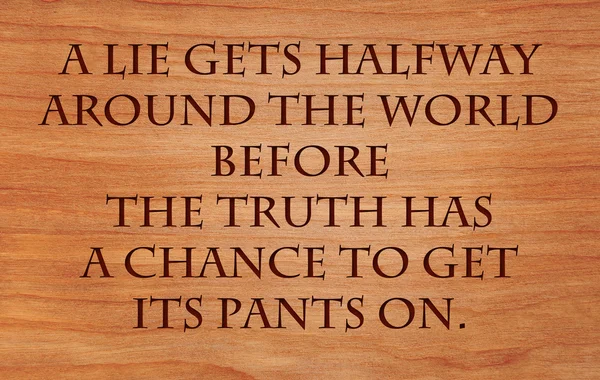 Брехня стає на півдорозі по всьому світу, перш ніж правда має шанс отримати свої штани цитати на дерев'яному червоному дубовому фоні — стокове фото