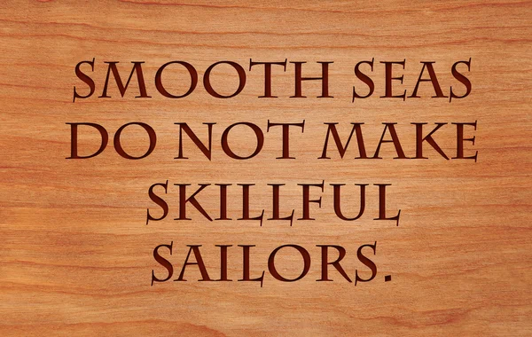 Smooth seas do not make skillful sailors - African Proverb on wooden red oak background — Stock Photo, Image
