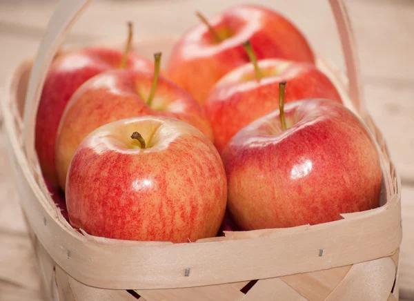 Gros plan de pommes rouges et jaunes dans un panier en bois sur fond de carton rustique — Photo