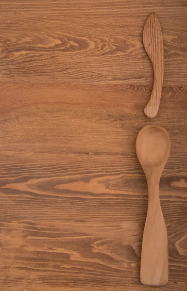 Houten lepel en een mes op de rechterkant van donkere houten tafelblad met kopie ruimte — Stockfoto