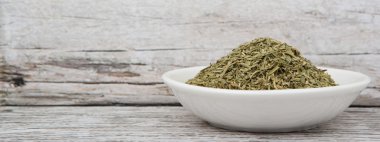 Ahşap arka plan üzerinde beyaz kase otlar tarhun kurutulmuş