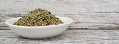 Ahşap arka plan üzerinde beyaz kase otlar tarhun kurutulmuş