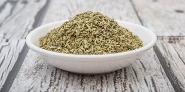 Ahşap arka plan üzerinde beyaz kase otlar tarhun kurutulmuş