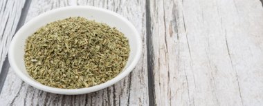 Ahşap arka plan üzerinde beyaz kase otlar tarhun kurutulmuş