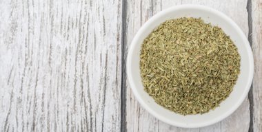 Ahşap arka plan üzerinde beyaz kase otlar tarhun kurutulmuş