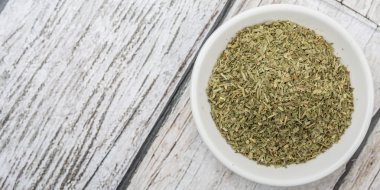 Ahşap arka plan üzerinde beyaz kase otlar tarhun kurutulmuş