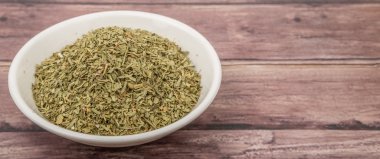 Ahşap arka plan üzerinde beyaz kase otlar tarhun kurutulmuş