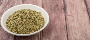 Ahşap arka plan üzerinde beyaz kase otlar tarhun kurutulmuş