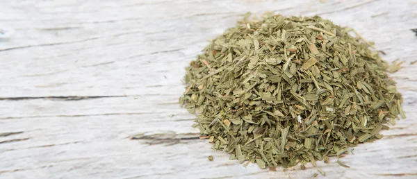Dried tarragon herbs over wooden background