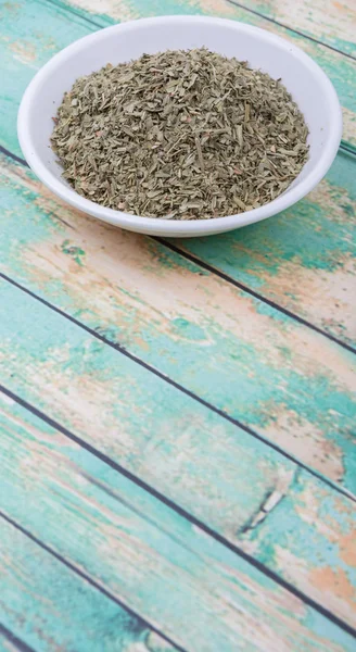 Dried tarragon herbs in white bowl over wooden background