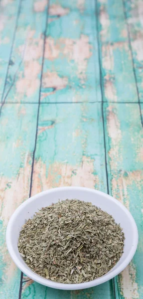 Dried tarragon herbs in white bowl over wooden background