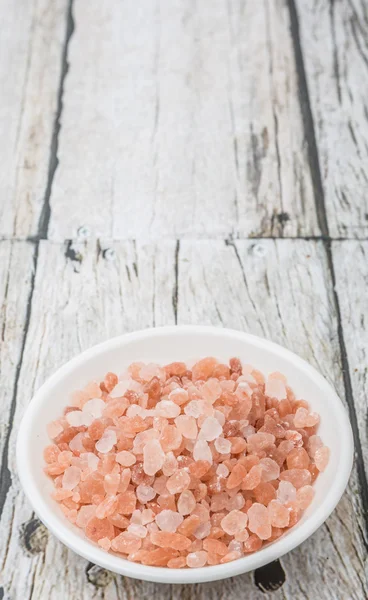 Himalayan rock salt in white bowl over wooden background