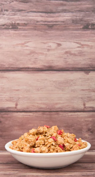 Frukostflingor Med Torkade Hallon Bitar Vit Skål Över Trä Bakgrund — Stockfoto