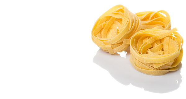 Dried tagliatelle pasta over white background