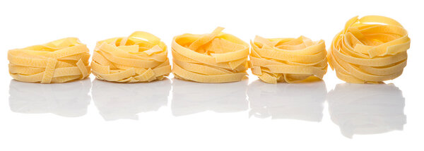 Dried tagliatelle pasta over white background