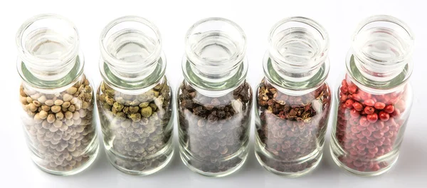 Variété de grains de poivre dans un flacon en verre — Photo