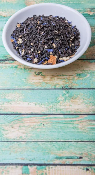Earl grey black tea in white bowl over wooden background