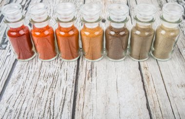 Soğuk toz, cayenne tozu, kırmızı biber tozu, karabiber toz, beyaz biber tozu, karabiber toz ahşap arka plan üzerinde cam şişe içinde ürün yelpazesine