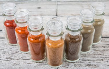 Soğuk toz, cayenne tozu, kırmızı biber tozu, karabiber toz, beyaz biber tozu, karabiber toz ahşap arka plan üzerinde cam şişe içinde ürün yelpazesine