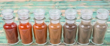 Soğuk toz, cayenne tozu, kırmızı biber tozu, karabiber toz, beyaz biber tozu, karabiber toz ahşap arka plan üzerinde cam şişe içinde ürün yelpazesine