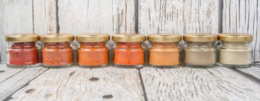 Sıcak ve baharatlı baharat tozu, kırmızı toz, soğuk toz, biber tozu, kırmızı biber tozu, karabiber ve küçük mason kavanoza ahşap arka plan üzerinde beyaz biber tozu