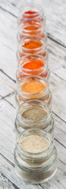 Sıcak ve baharatlı baharat tozu, kırmızı toz, soğuk toz, biber tozu, kırmızı biber tozu, karabiber ve küçük mason kavanoza ahşap arka plan üzerinde beyaz biber tozu