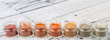 Sıcak ve baharatlı baharat tozu, kırmızı toz, soğuk toz, biber tozu, kırmızı biber tozu, karabiber ve küçük mason kavanoza ahşap arka plan üzerinde beyaz biber tozu