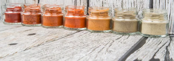 Hot and spicy spices powder, cayenne powder, chilly powder, peppercorn powder, paprika powder, black pepper and white pepper powder in small mason jar over wooden background
