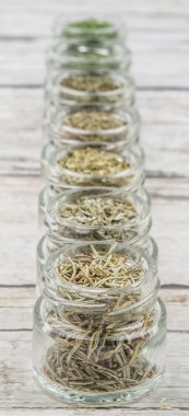 Kurutulmuş maydanoz, roka, mercanköşk, dereotu, kafiye, biberiye ve basil otlar ahşap arka plan üzerinde mason kavanoza