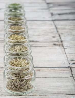 Kurutulmuş maydanoz, roka, mercanköşk, dereotu, kafiye, biberiye ve basil otlar ahşap arka plan üzerinde mason kavanoza