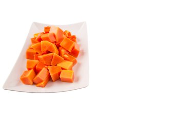 Beyaz arka plan üzerinde beyaz tabakta ısırık büyüklüğünde papaya meyve