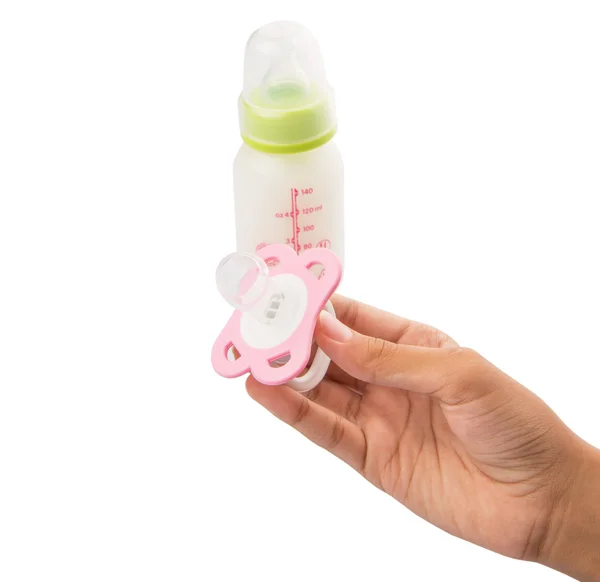 Vrouwelijke hand met een roze fopspeen met een fles van baby's melk — Stockfoto