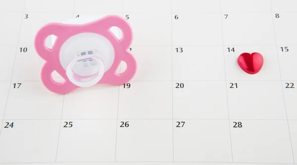 Roze fopspeen en kalender — Stockfoto