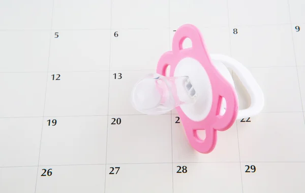 Roze fopspeen en kalender — Stockfoto