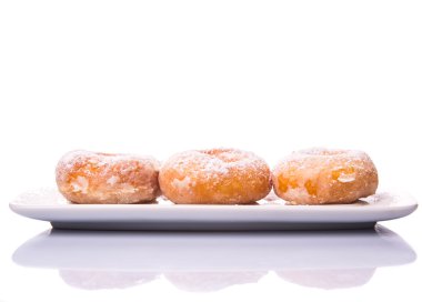 Beyaz arka plan üzerinde beyaz bir tabakta şeker toppings ile ev yapımı çörek