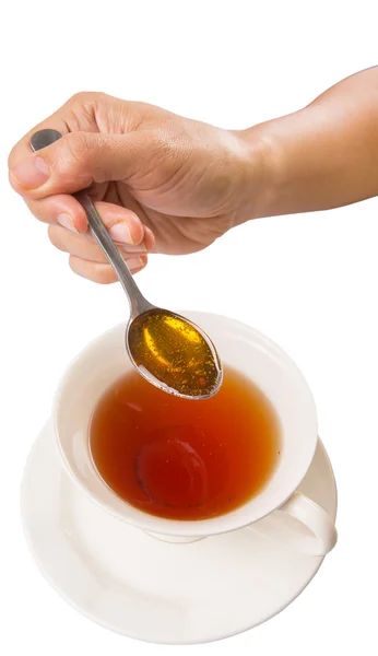 Vrouwelijke Hand mengen honing met thee — Stockfoto