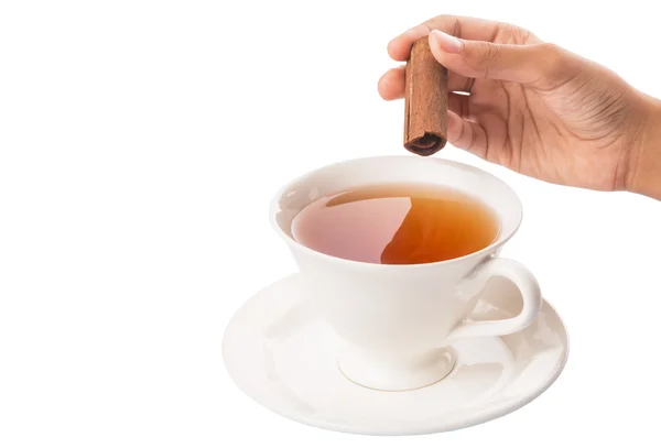 Mano femenina con una taza de té y palillo de canela — Foto de Stock