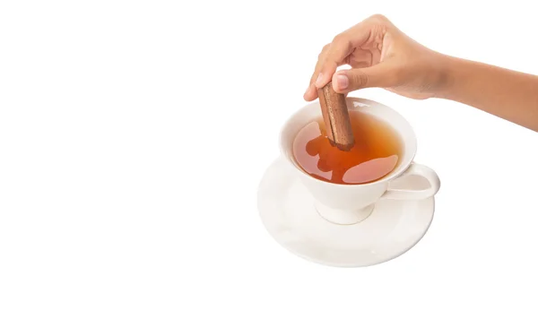 Main féminine avec une tasse de thé et bâton de cannelle — Photo