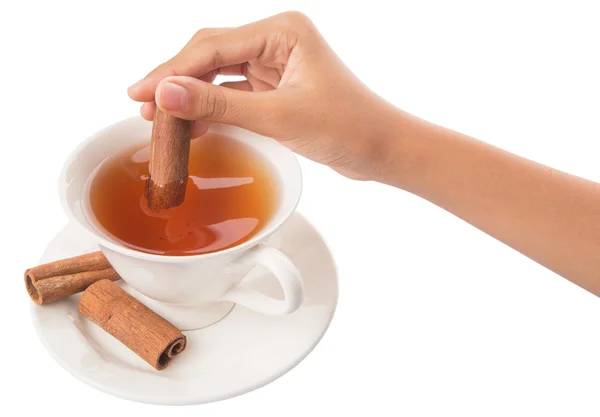 Main féminine avec une tasse de thé et bâton de cannelle — Photo