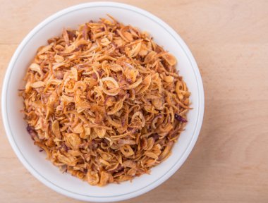 Ahşap yüzey üzerinde beyaz kase süsleme için derin kızarmış arpacık