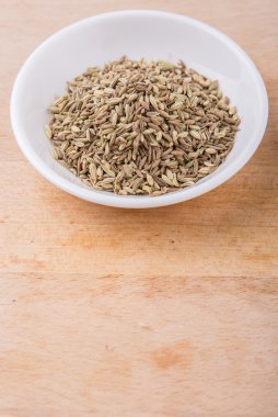 Kimyon tohum baharat ahşap yüzey üzerinde beyaz kase