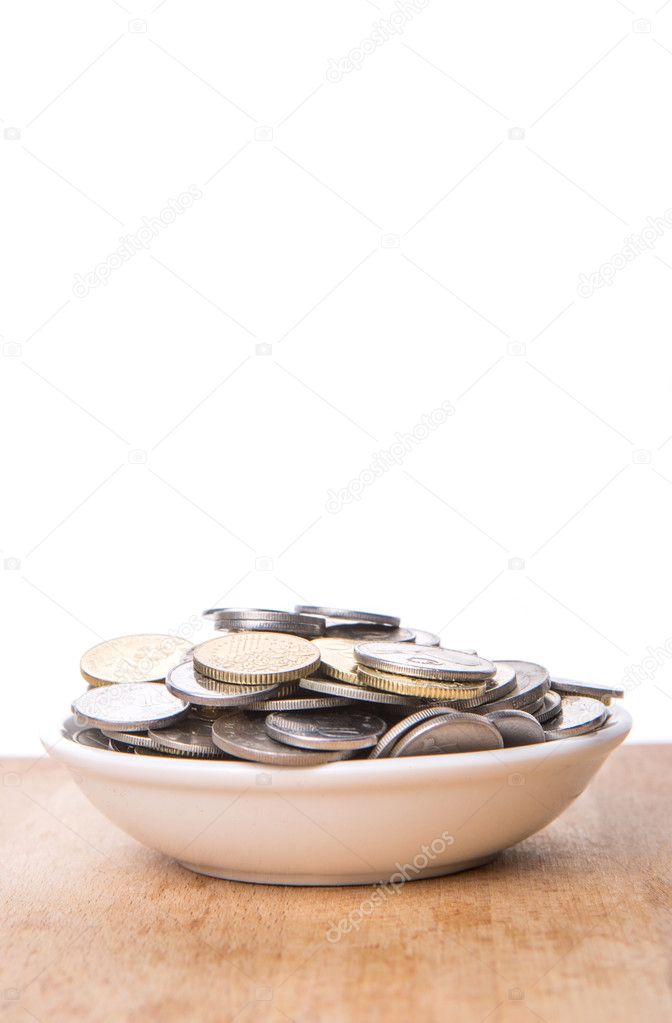 Malaysian coins in a white bowl over wooden surface