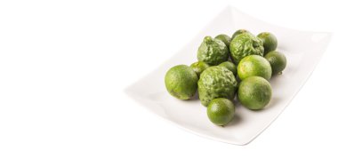 Kireç, makrut veya Güney Afrika'da bir kabile kireç ve beyaz arka plan üzerinde beyaz tabakta calamansi