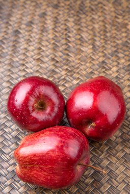 Hasır arka plan üzerinde kırmızı elmalar