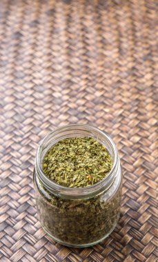 Maydanoz otlar bir mason kavanoza Hasır arka plan üzerinde kurutulmuş