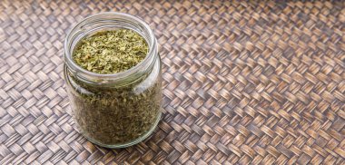 Maydanoz otlar bir mason kavanoza Hasır arka plan üzerinde kurutulmuş