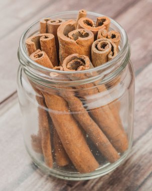 Kabuk tarçın baharat yıpranmış ahşap arka plan üzerinde bir mason kavanoza