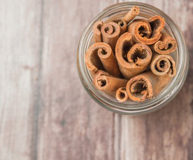 Kabuk tarçın baharat yıpranmış ahşap arka plan üzerinde bir mason kavanoza