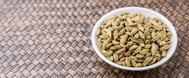 Kakule baharat beyaz Hasır arka plan üzerinde kase